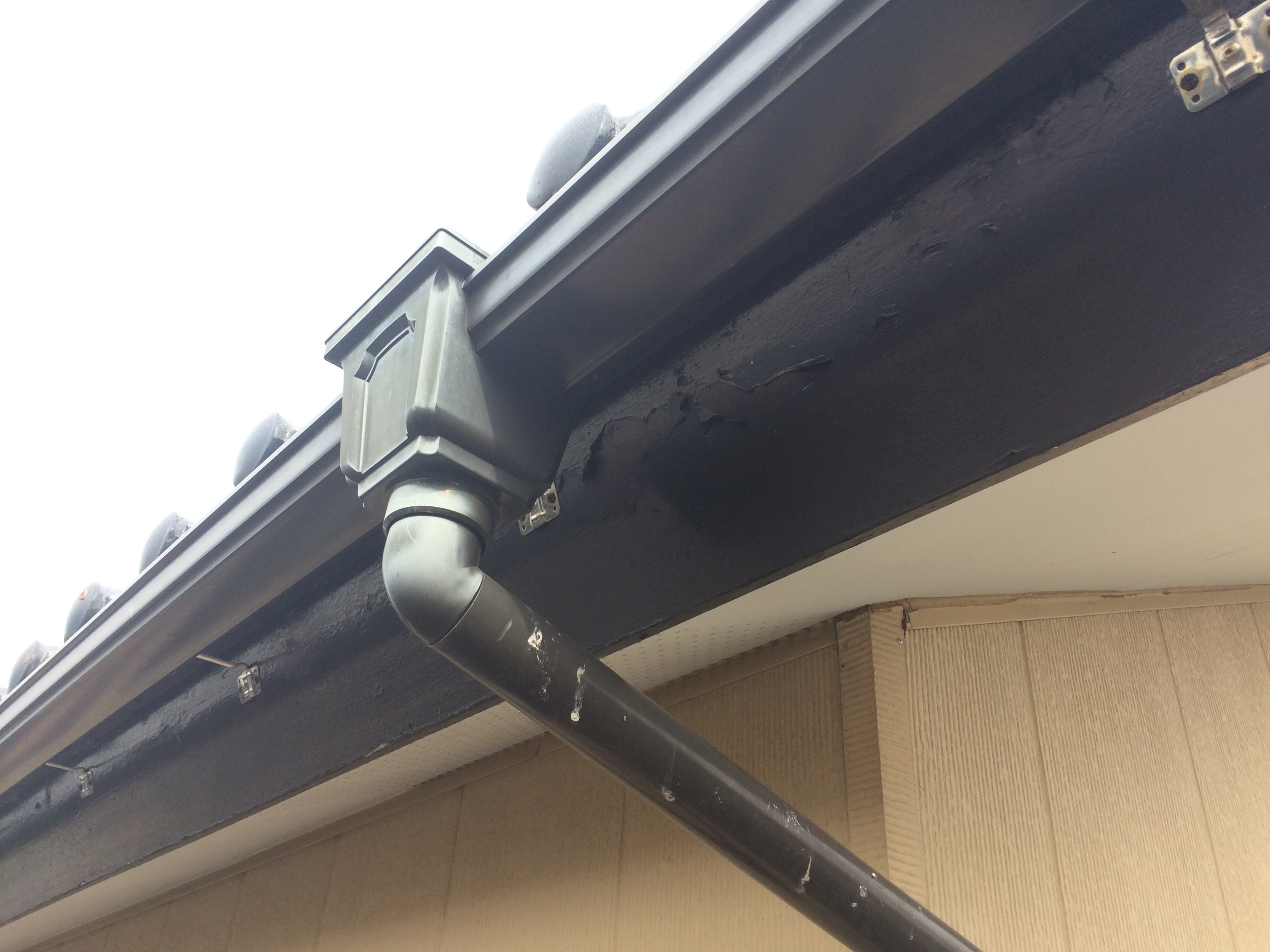 雨とい掃除修理のトップ瓦屋根、茶色い破風、吊り金具写真